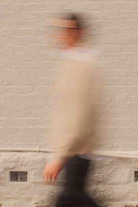 Un hombre caminando, desenfocado, frente a una pared