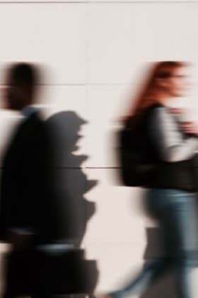 Personas caminando frente a una pared blanca